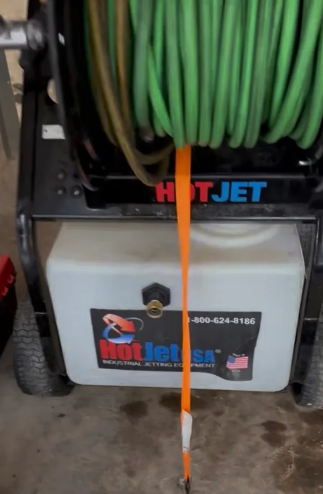 Green jetting hose wound on a reel above the equipment water tank in Utah.