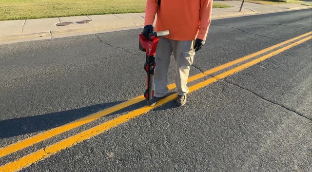A crew member using an underground line locator on a paved road in Utah.