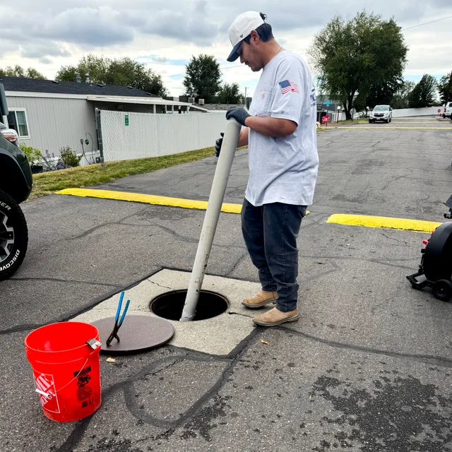 Mountain West technician guiding a pipe into a sewer access opening in Utah.